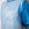 A close-up of a light blue disposable protective gown or bib with a solid blue collar and sleeve, shown on a person against a plain light background.