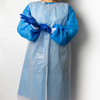 A person wearing a light blue protective gown with blue gloves, shown against a plain light gray background.